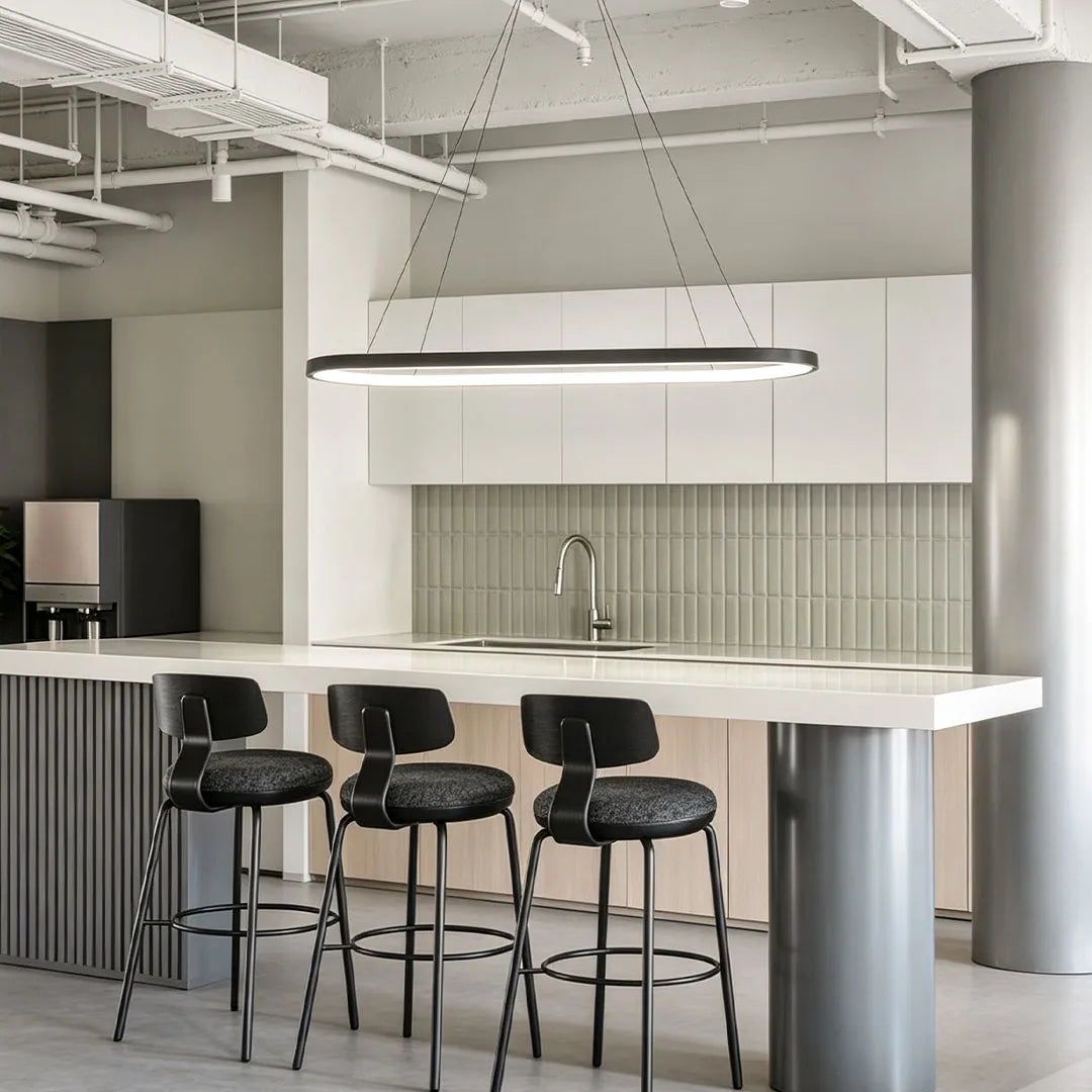 Oval pendant light hanging above a white kitchen island in a modern industrial-style interior with exposed ceiling details.