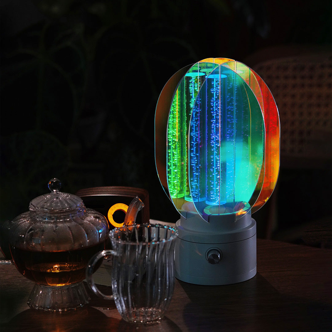 Oval colourful table lamp projecting bright rainbow light onto a bedroom wall, creating a dynamic, playful atmosphere.