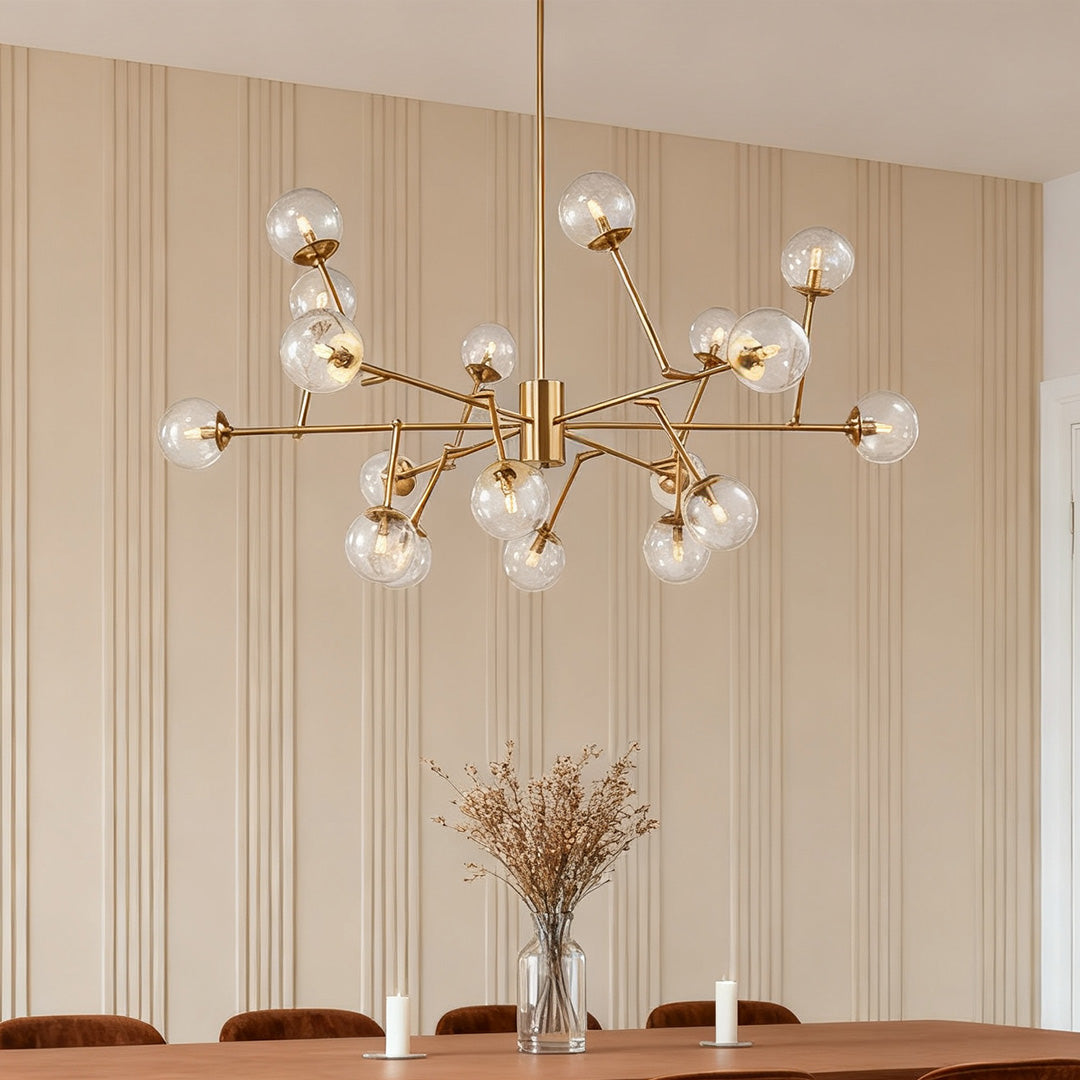 Oversized bubble sputnik chandelier with clear glass shades and a brass finish, providing a modern centerpiece above a long dining table.
