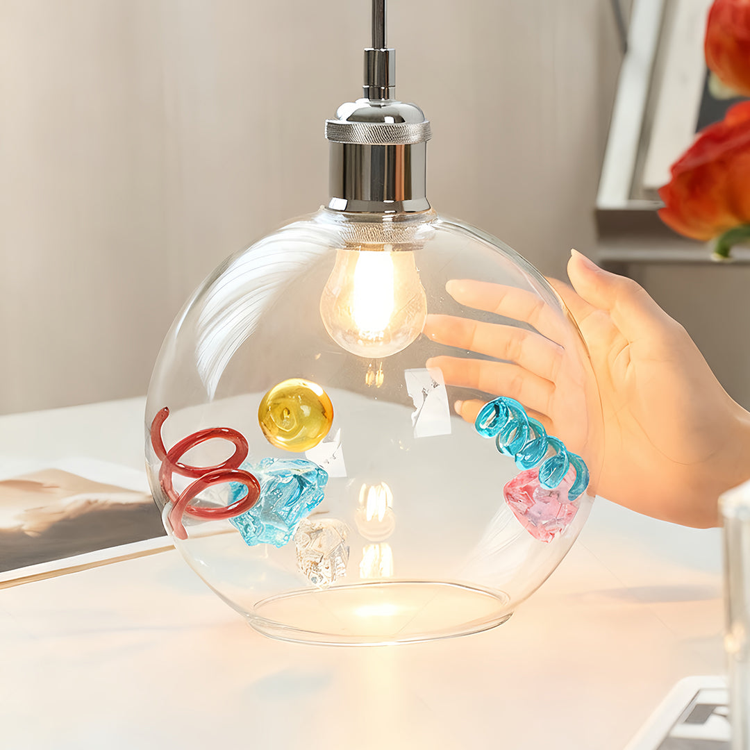 Oversized globe coloured glass pendant lights being handled to show size and artistic inlay on a tabletop.