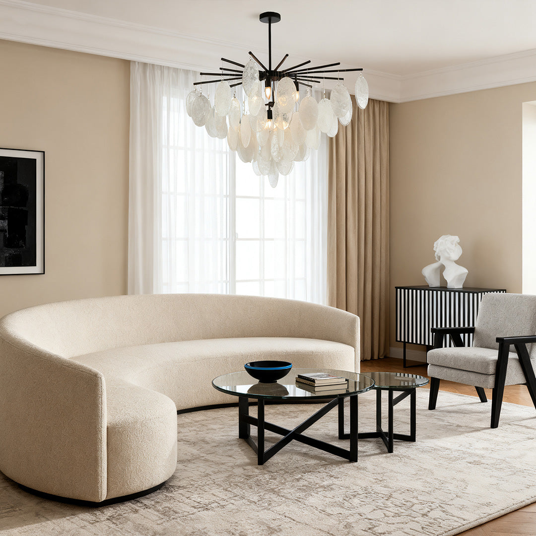 Oversized mother of pearl chandelier providing soft, diffuse light in a contemporary living room with a curved sofa and black accents.