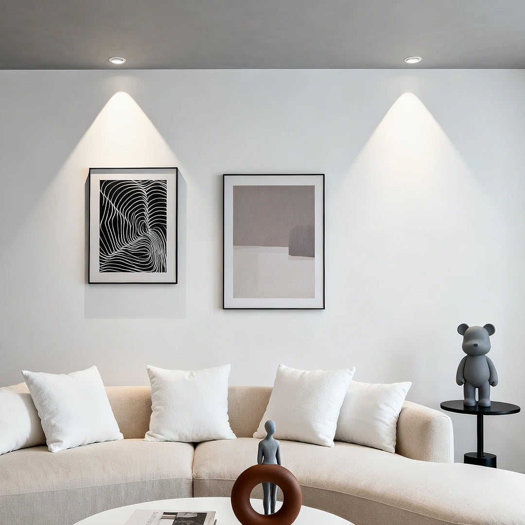 Pair of accent spotlights illuminating contemporary living room with beige sofa and framed artwork