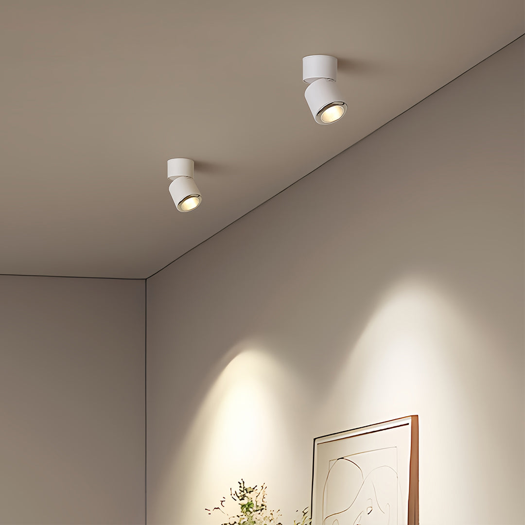 Pair of adjustable spotlights mounted on beige ceiling corner creating focused wall illumination