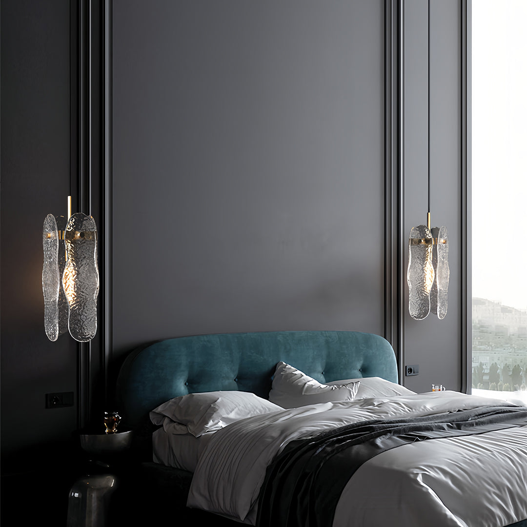 Pair of brass glass pendant lights flanking dark grey bedroom with blue accent chair.
