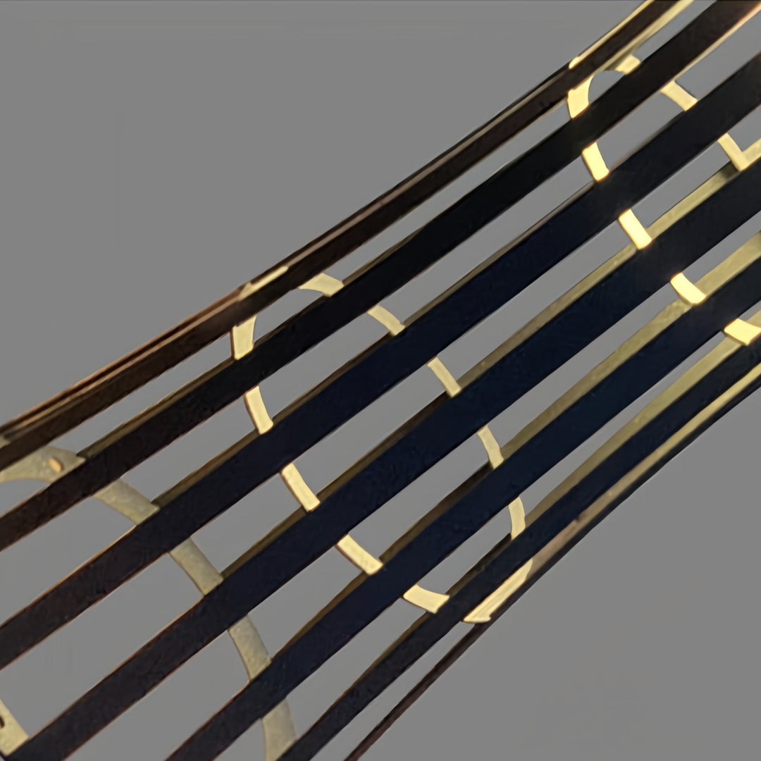 Pair of different-sized outdoor black lanterns with woven cage design lighting a stone border and steps on a modern patio.