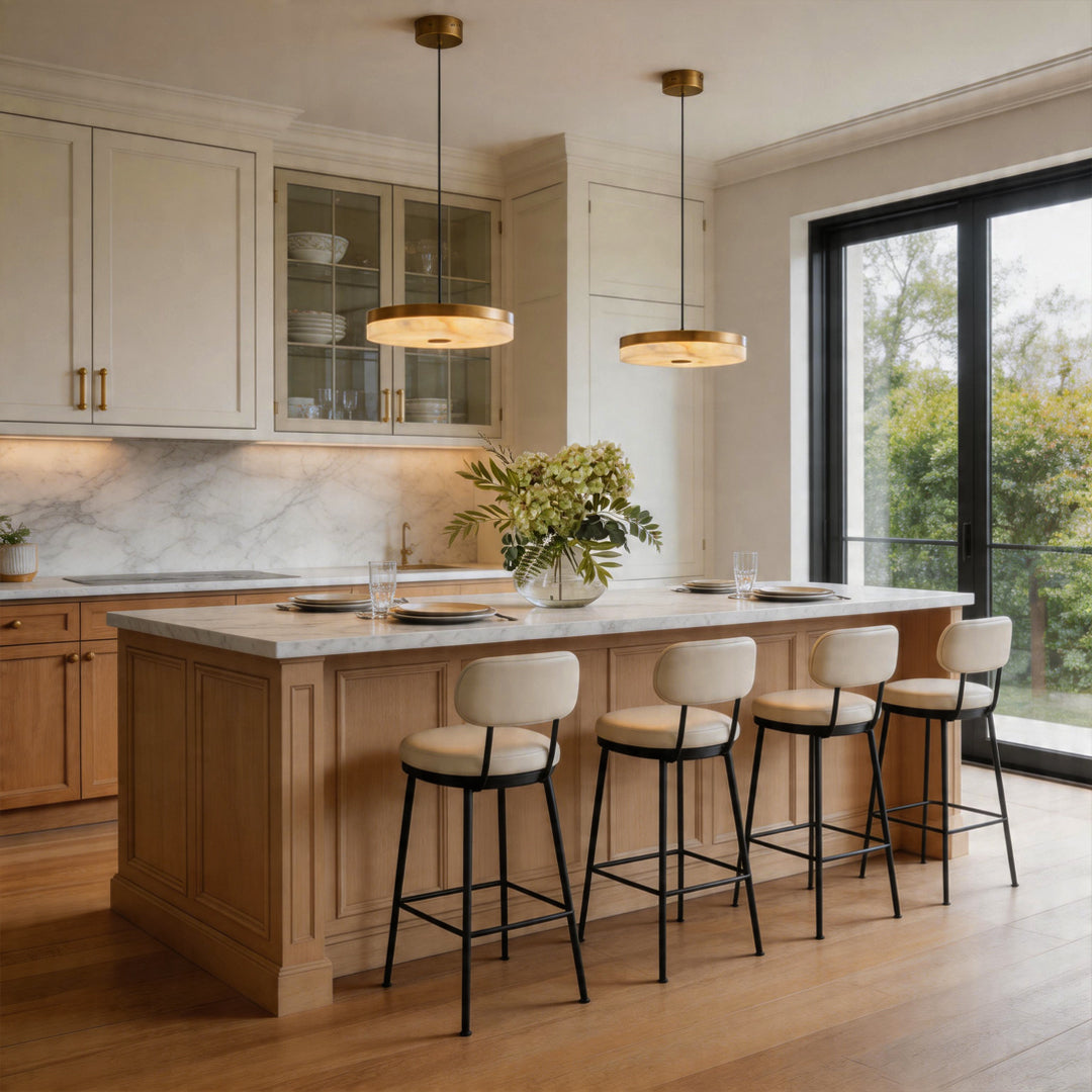 Pair of disc pendant light fixtures illuminating a white marble kitchen island and bar stools.