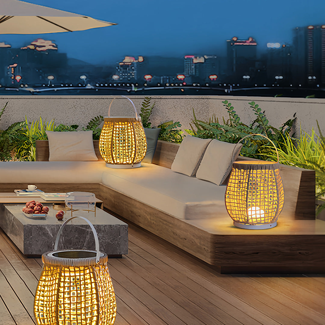 Pair of illuminated woven outdoor lanterns with white bases, creating a cozy ambiance on a modern rooftop patio lounge at night.