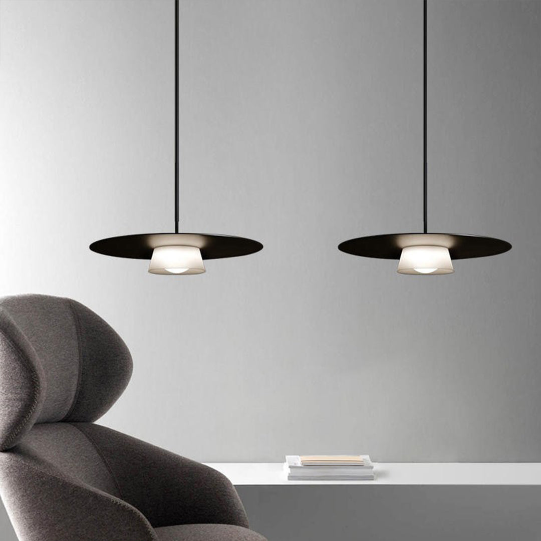 Pair of island pendant light fixtures positioned over contemporary seating area with gray chairs