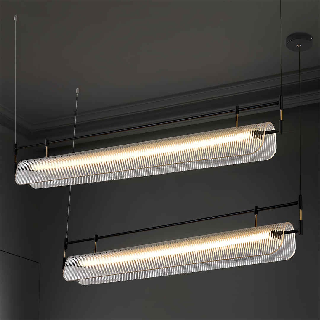 Pair of linear light pendants with dramatic lighting effect against dark wall in contemporary space.