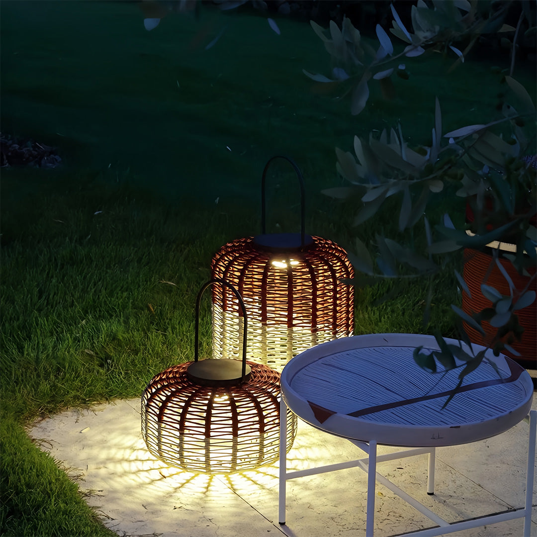 Pair of varying height outdoor LED lantern lights with a mushroom-shaped base, sitting on a stone patio next to a small white table.