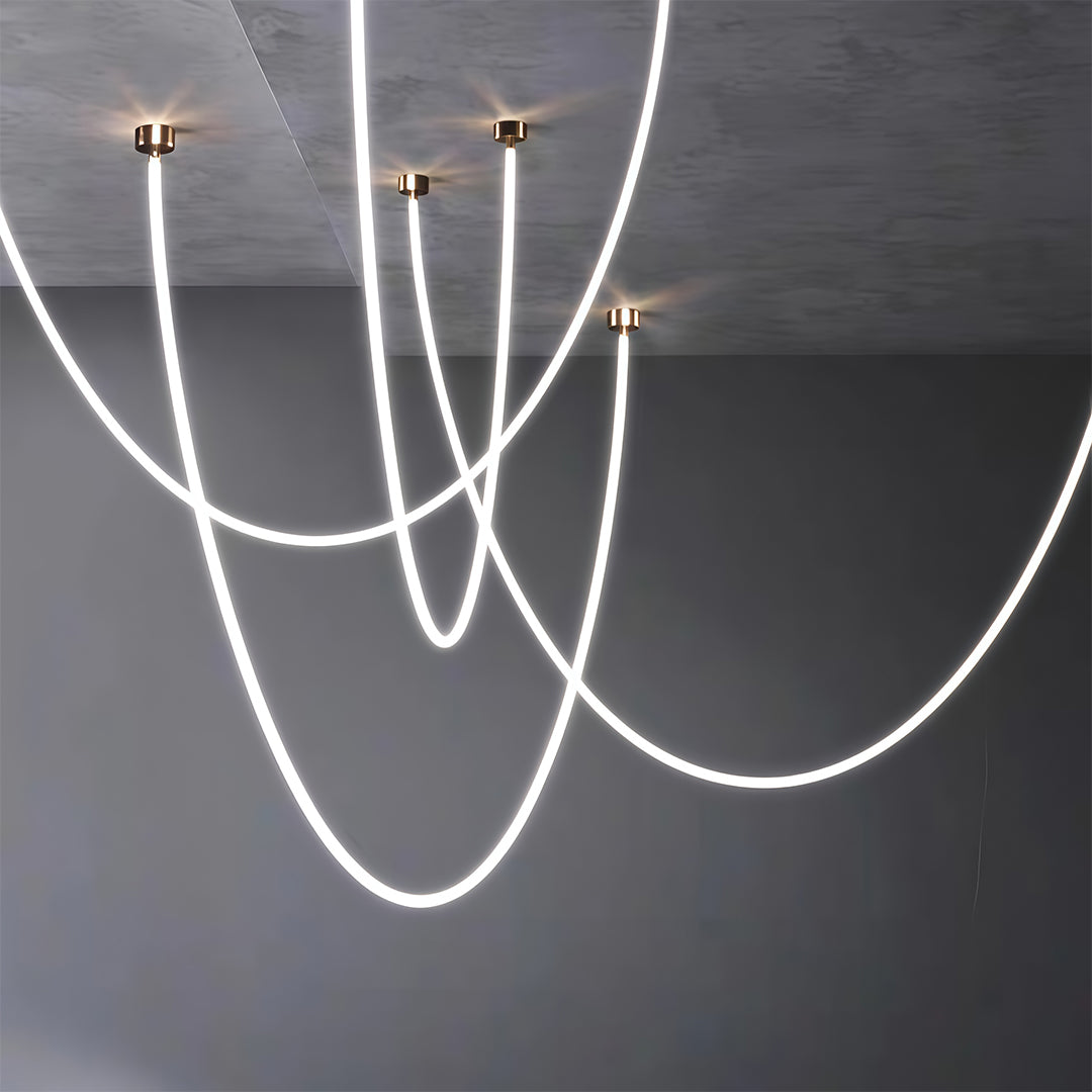 Pair of neon pendant lights creating overlapping curves on dark grey surface with dramatic contrast.