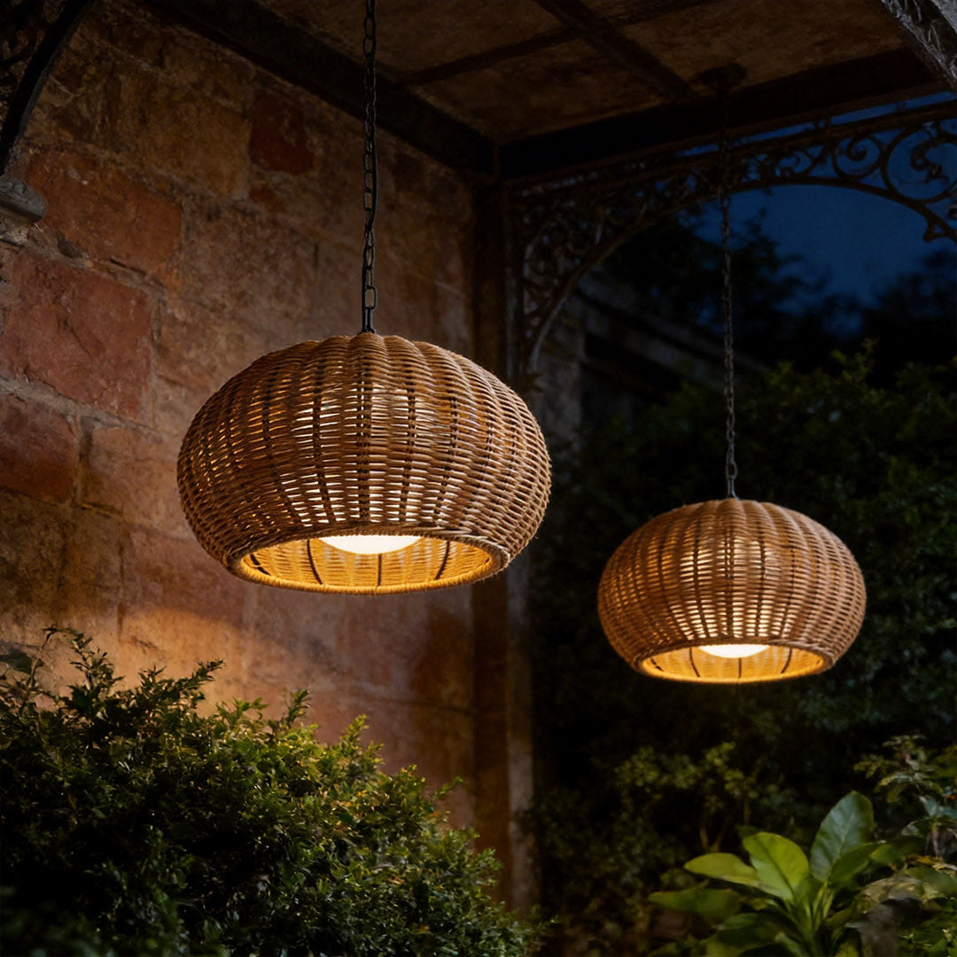 Pair of rattan outdoor pendant lights illuminating a cozy brick porch area during the nighttime.