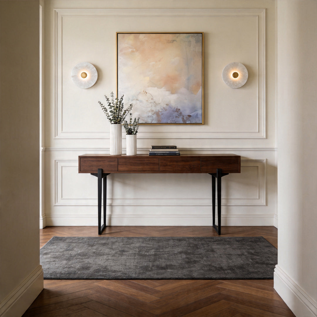 Pair of round wall lights flanking abstract artwork in a luxury hallway with a console table.