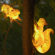 Pair of illuminated squirrel solar lights creating magical lighting effect in garden setting