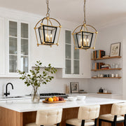 Pair of tiered gold lantern pendant light fixtures illuminating a white kitchen island with modern black and white accents.