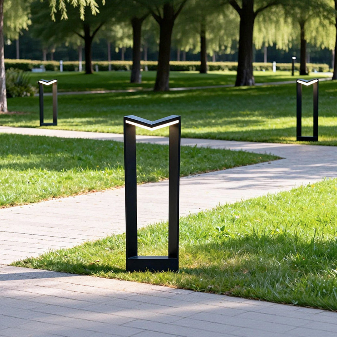 Square bollard light used along a park pathway creating structured and uniform outdoor lighting.