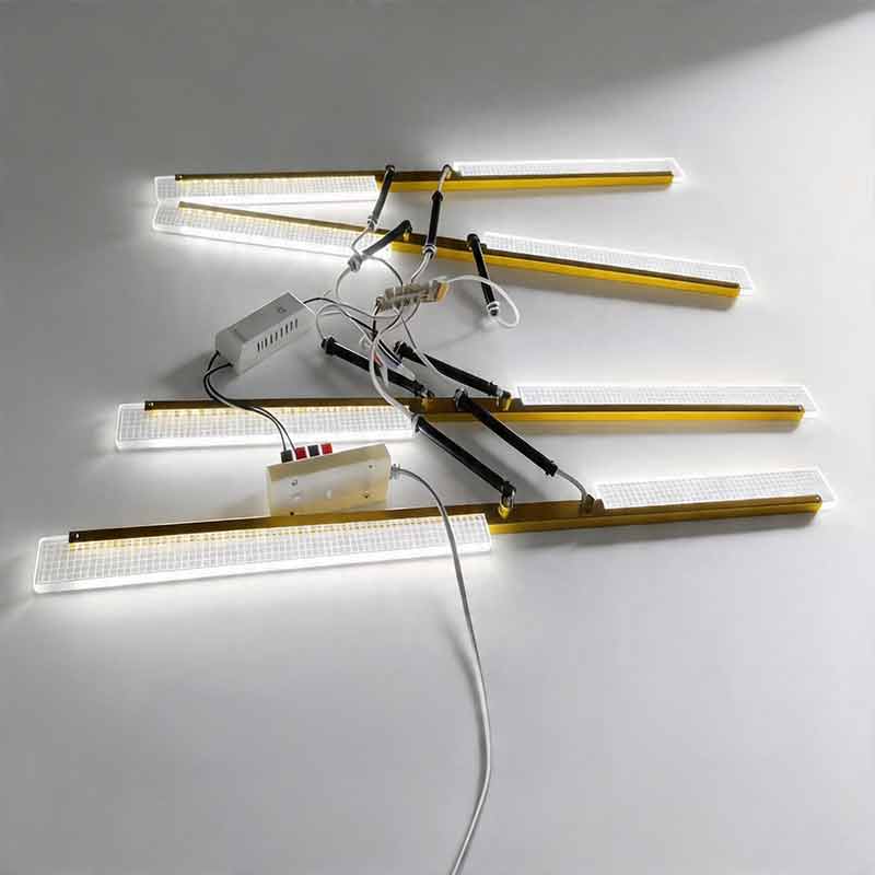 Partially assembled Gold cross ceiling light showing glowing linear LED panels and inner wires.