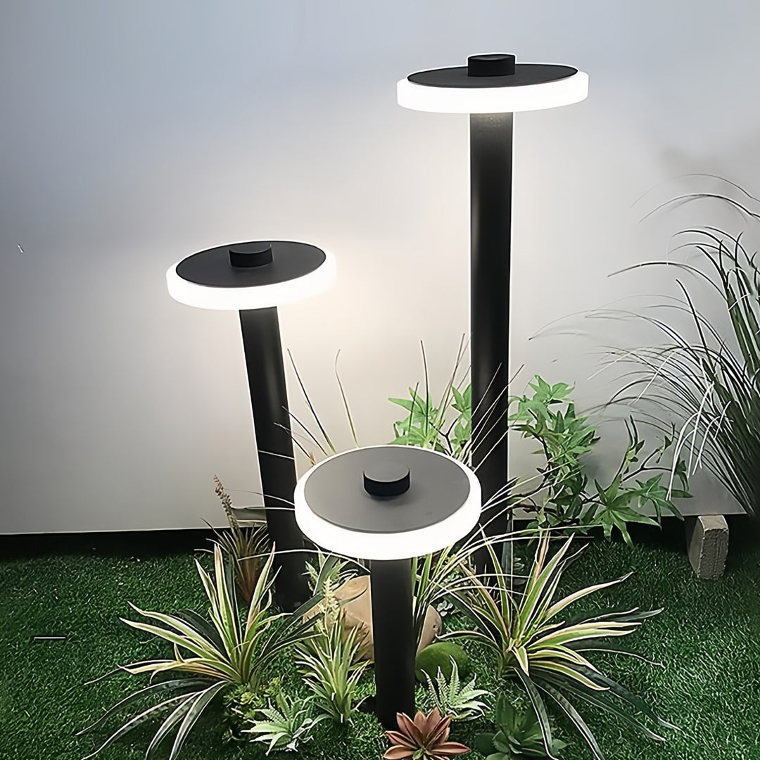 Tall black path lighting outdoor poles illuminating lush greenery in a residential garden.