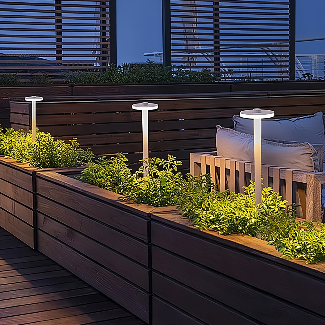 Contemporary path lighting outdoor posts illuminating a raised planter area in an urban garden.