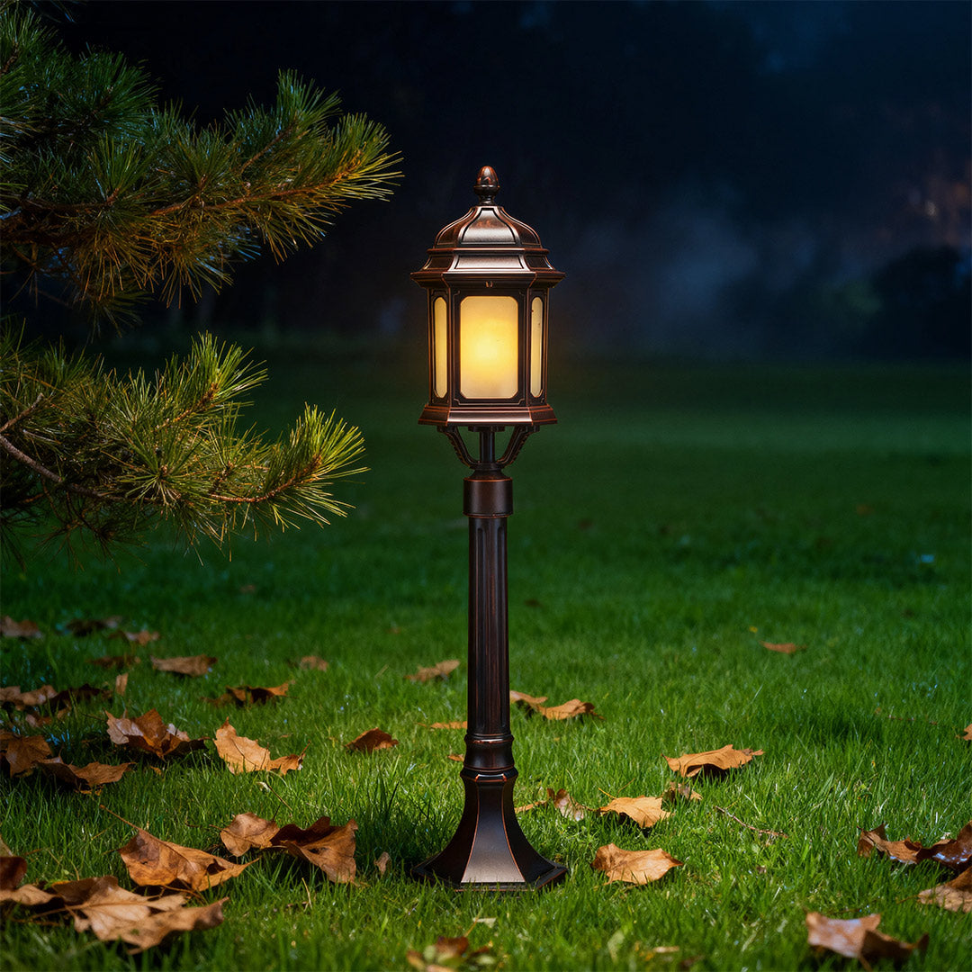 Single path post light glowing warmly on green lawn in evening residential garden setting