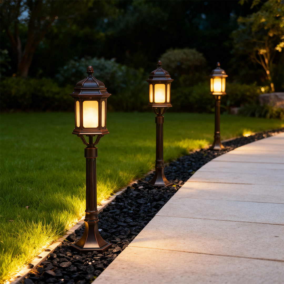 Multiple path post lights illuminating curved concrete walkway through landscaped lawn at night