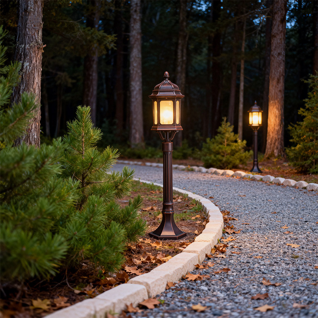 Path post lights lining gravel pathway through wooded garden area creating warm ambient lighting