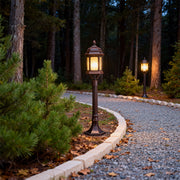 Path post lights lining gravel pathway through wooded garden area creating warm ambient lighting