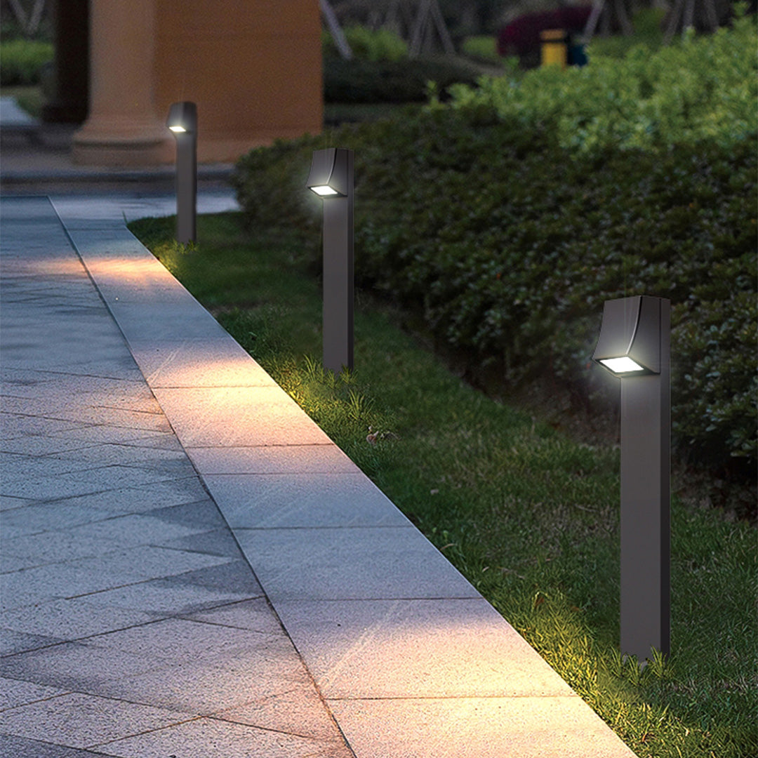 Multiple black bollard lights lining a paved walkway at dusk