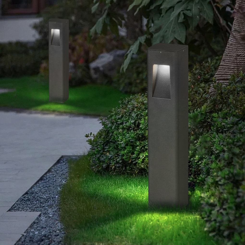 Pathway bollard lights casting a warm glow on a driveway leading to a modern house.