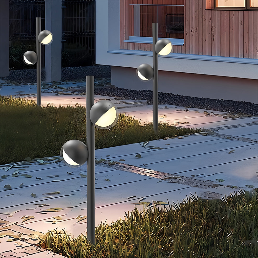 Pathway landscape lighting system in contemporary backyard with multiple posts along stone border creating layered lighting
