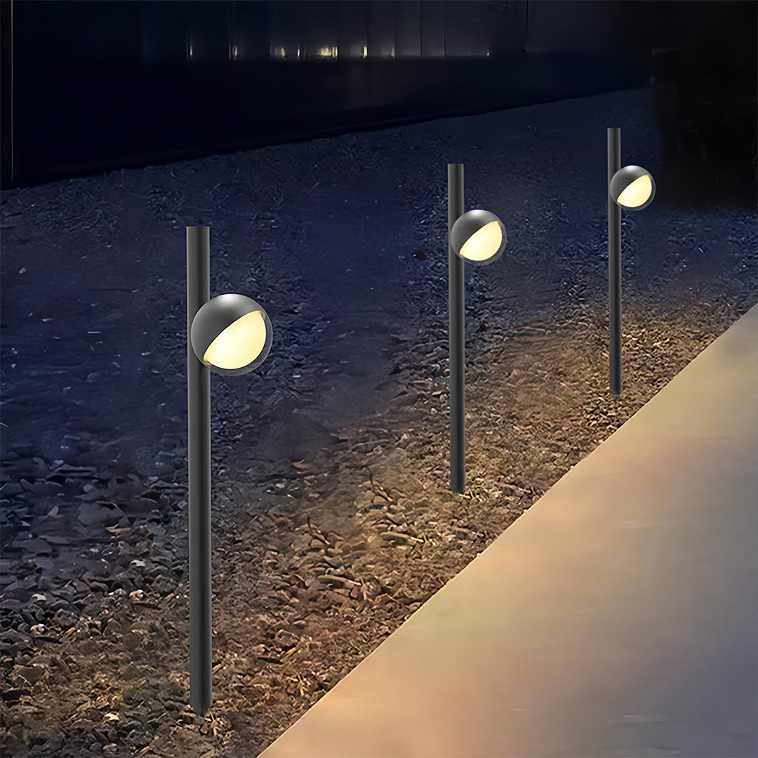Pathway landscape lighting installed along gravel border at night creating dramatic illuminated walkway effect