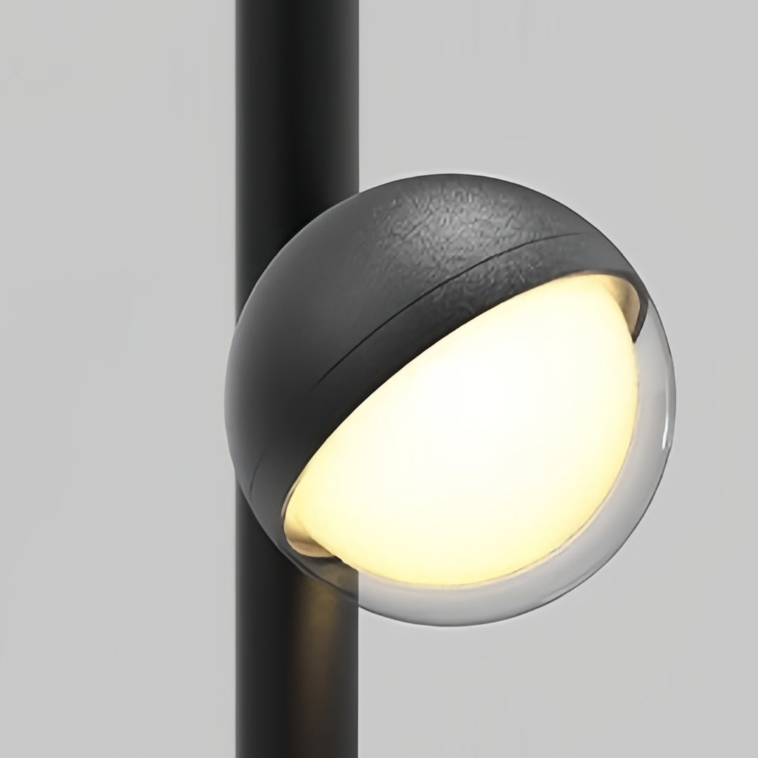 Pathway landscape lighting featuring spherical adjustable head on black post creating warm directional glow