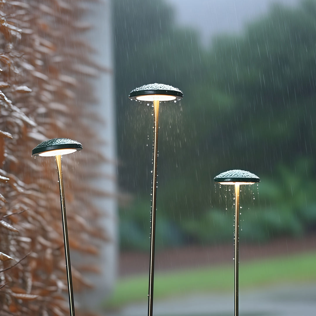 A minimal black outdoor lamp placed in a grassy field, providing gentle and focused pathway outdoor lighting for open landscapes.
