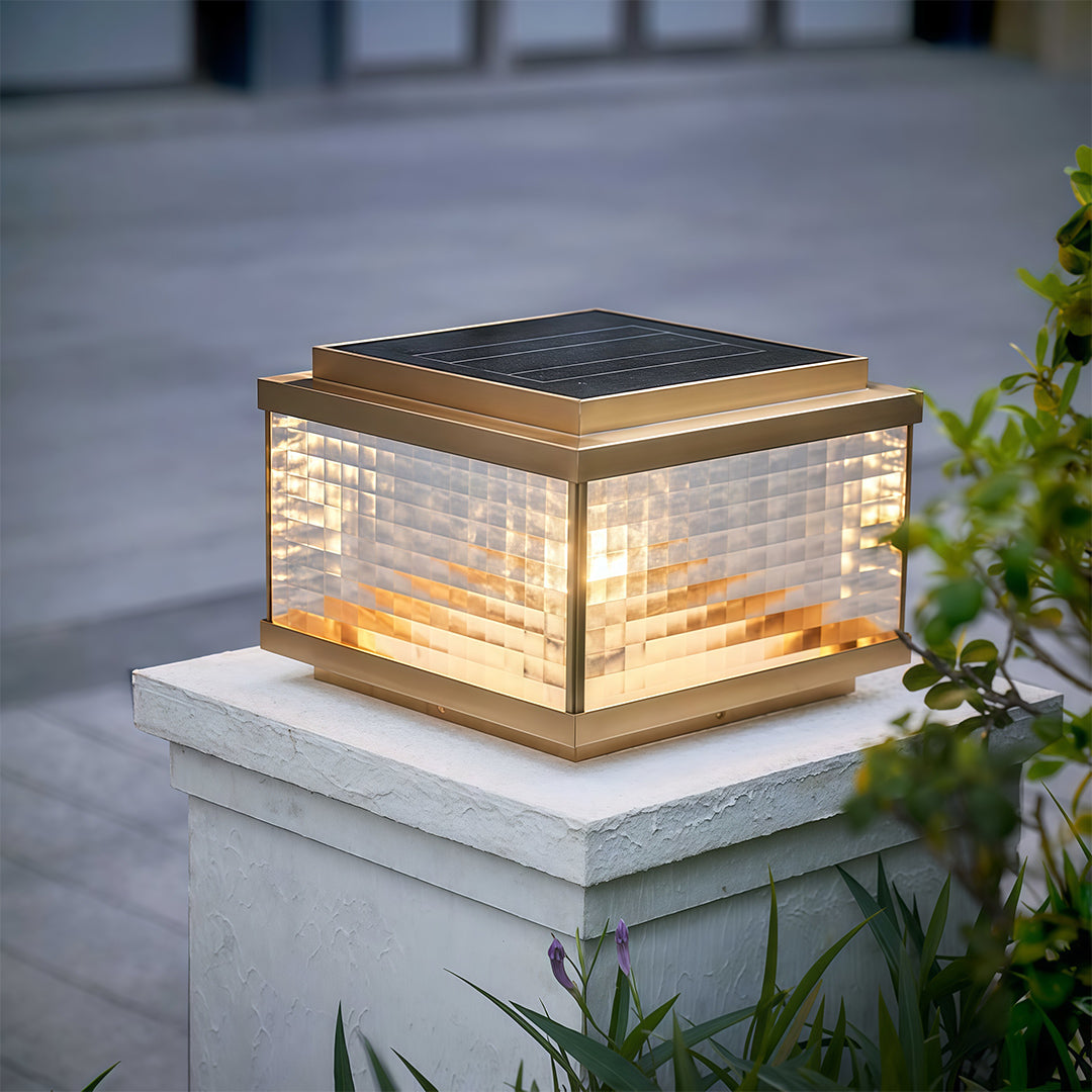 Pillar cap light on concrete post illuminating paved outdoor pathway with warm evening glow