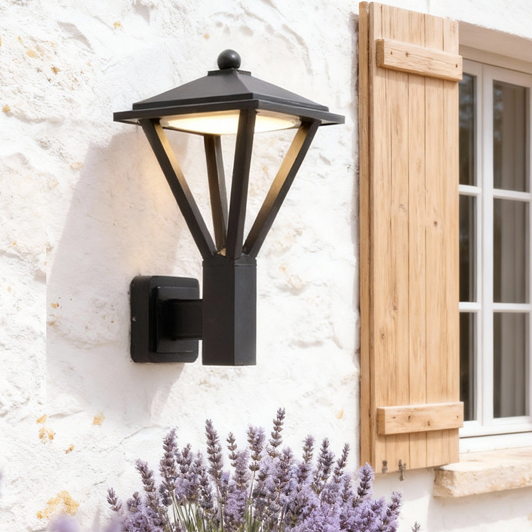 Black lantern-style outdoor wall light illuminating a cozy patio area, ideal for warm and inviting wall mounted lights outdoor.