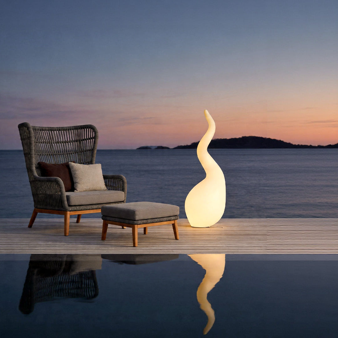 Patio outdoor floor lamps beside seaside deck seating creating warm ambient evening lighting.