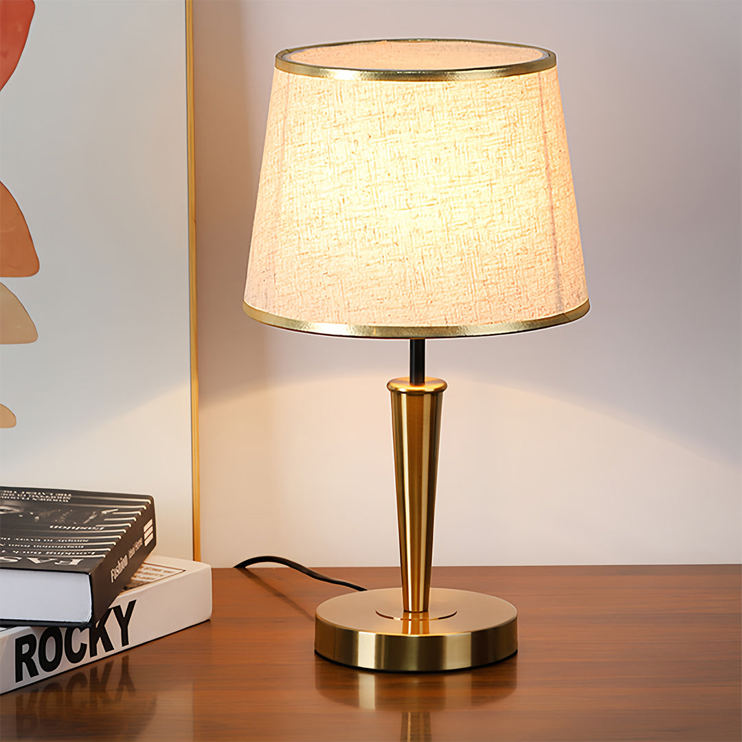 Modern brass table lamp with patterned shade creating warm atmospheric lighting