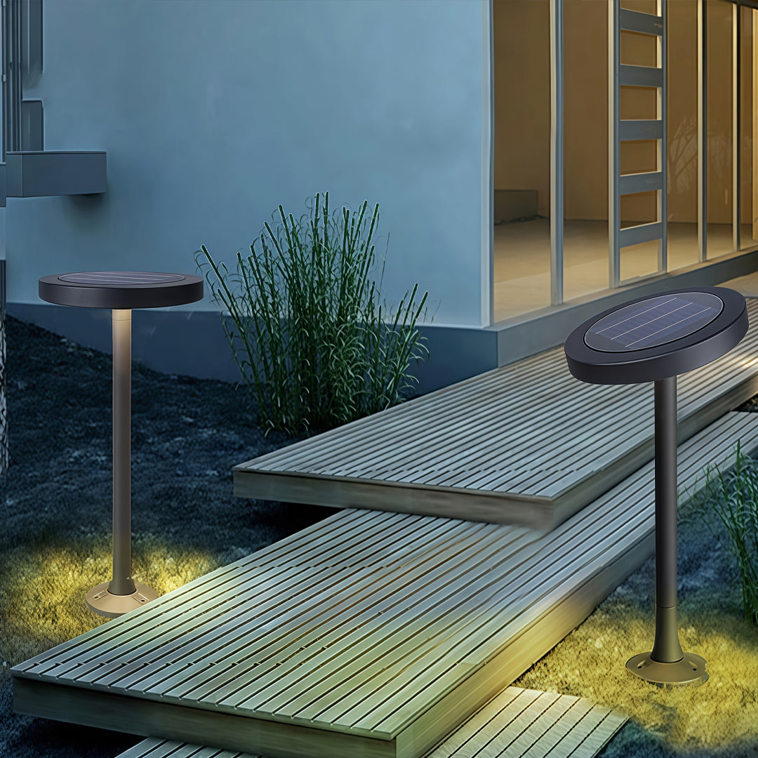 Outdoor modern path lights installed on paved walkway near building entrance with natural scenery.