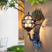 Peacock wall light illuminated on modern exterior wall at night.