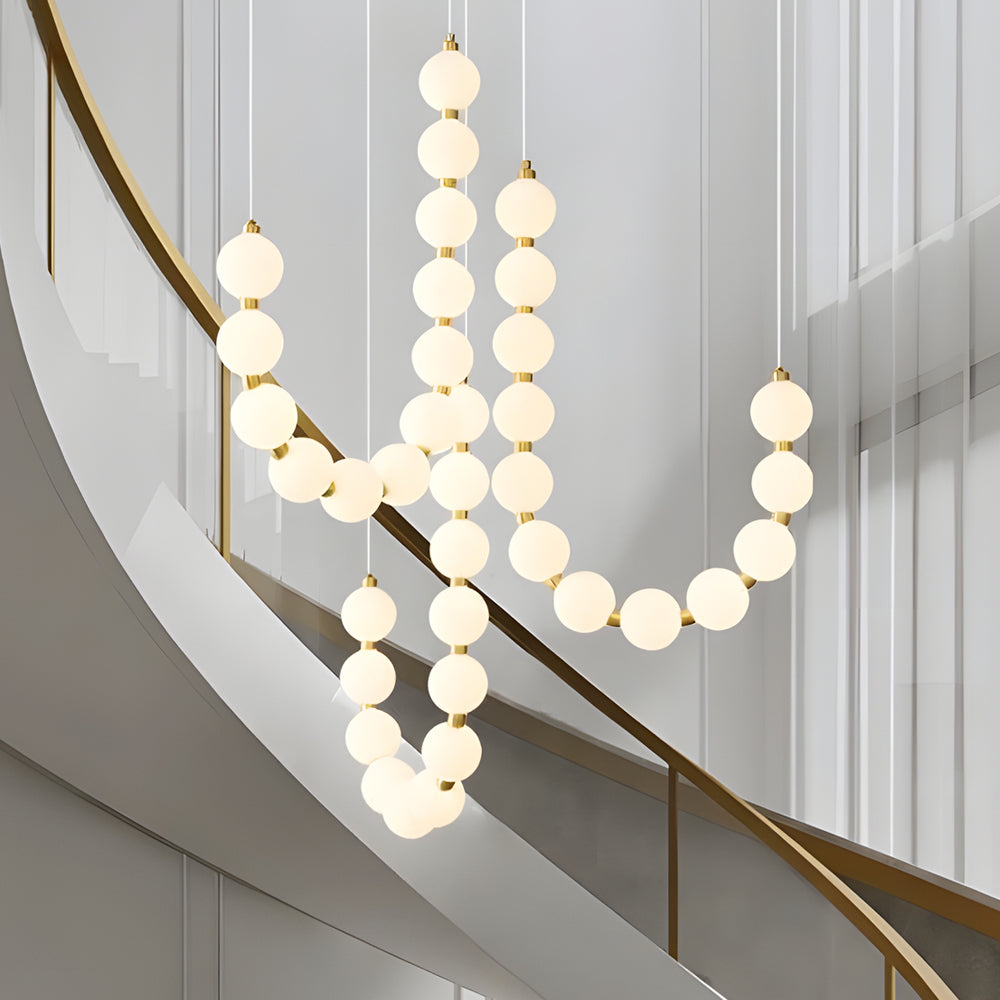 Pearl necklace light fixture with a golden chain, hanging along a staircase.