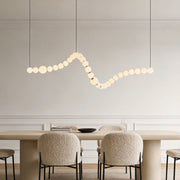 Pearl necklace light fixture with a sleek design, hanging above a modern dining table.