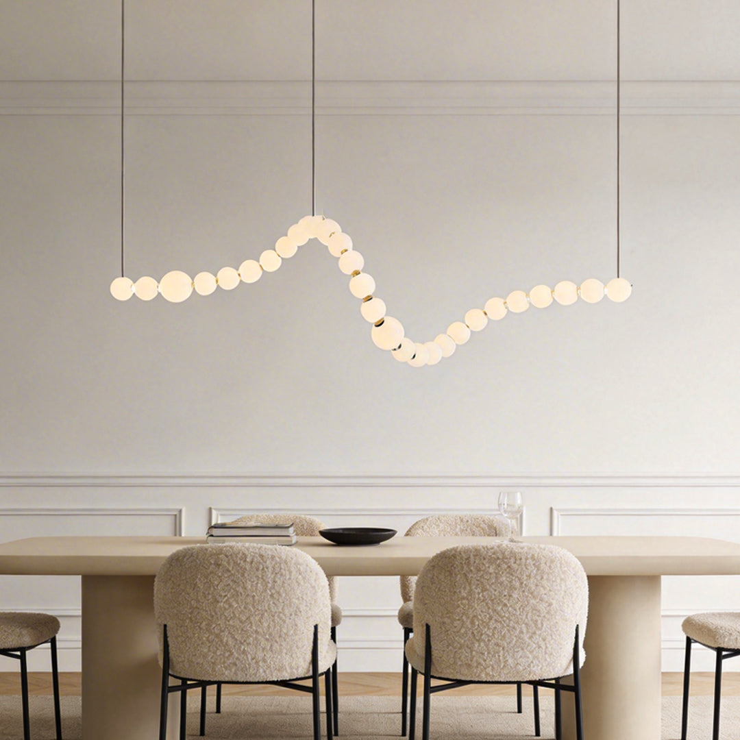 Pearl necklace light fixture with a sleek design, hanging above a modern dining table.