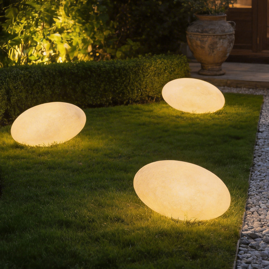 Pebble garden lights illuminating a modern lawn pathway with warm ambient glow.