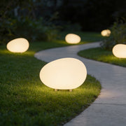 Pebble lights illuminating garden pathway with soft glow at dusk.