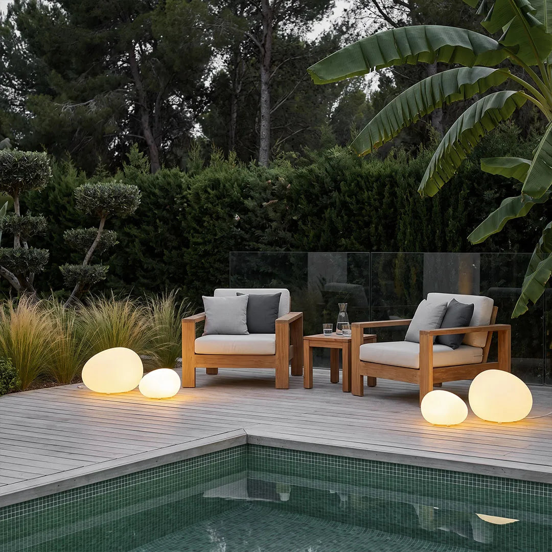 Pebble lights arranged around a modern pool patio with lounge chairs and tropical landscaping.