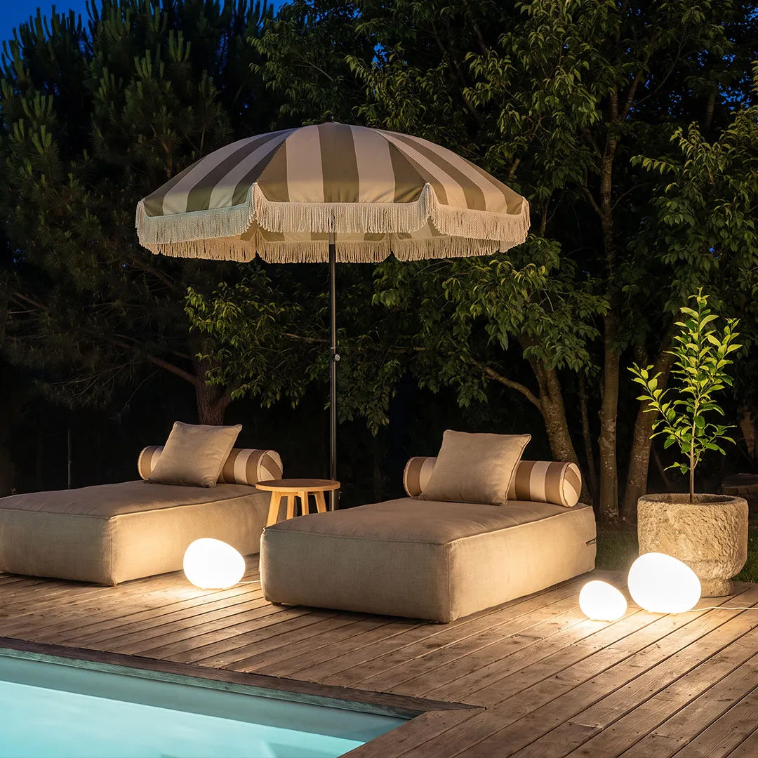 Pebble lights illuminating a poolside lounge area at night with soft glowing spheres around outdoor seating.