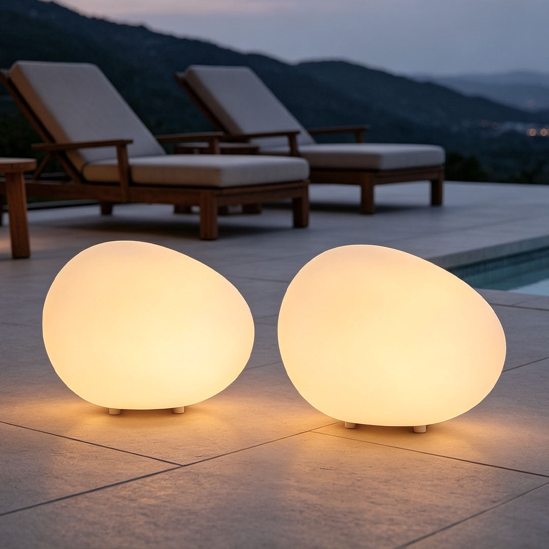 Pebble lights glowing beside a swimming pool, featuring smooth round forms that create soft ambient outdoor illumination.