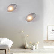 Pebbles wall lamp casting a gentle light in a contemporary living room with a gray sofa.