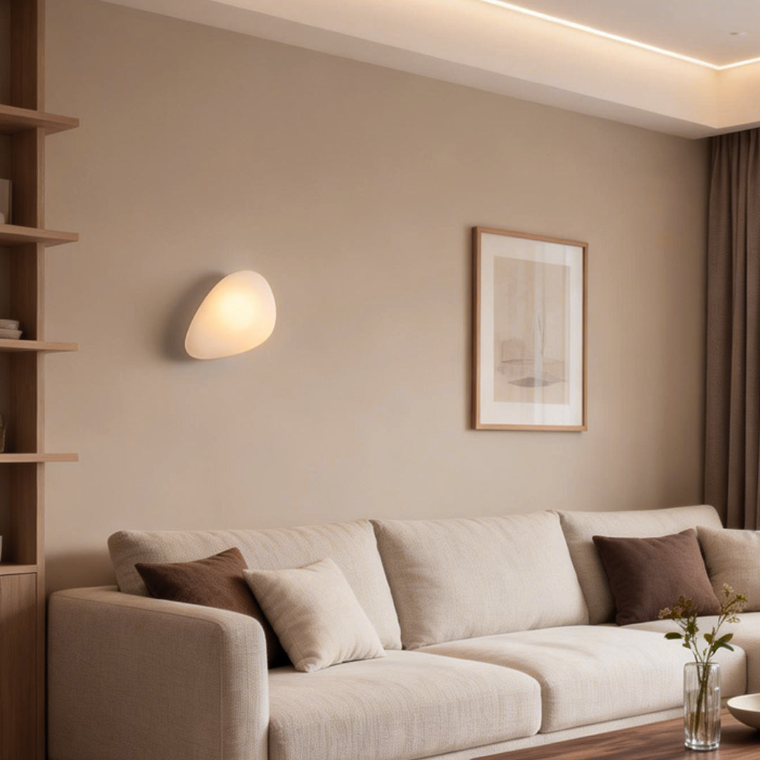 Pebbles wall lamp with a soft light, enhancing the ambiance of a white bedroom.