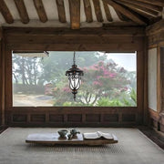 Pendant light fixture suspended in covered outdoor patio with exposed wooden beams